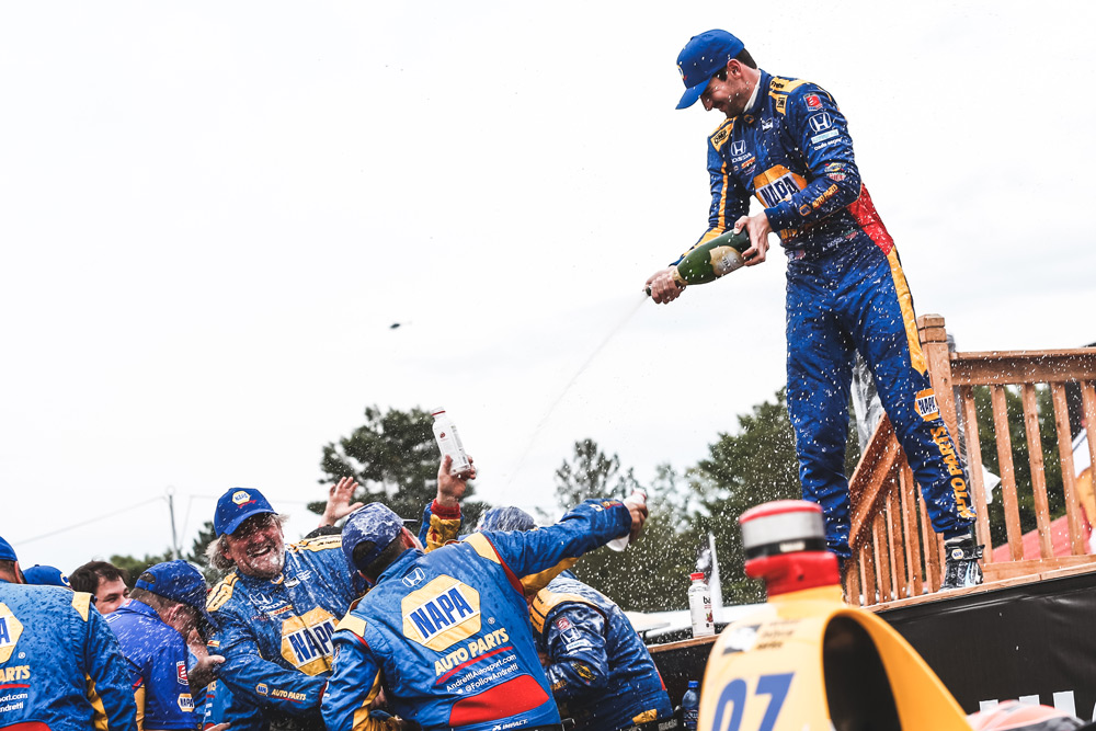 Alexander Rossi gives his Andretti Autosport team a champagne shower in Victory Circle after winning the Honda Indy 200 at Mid-Ohio